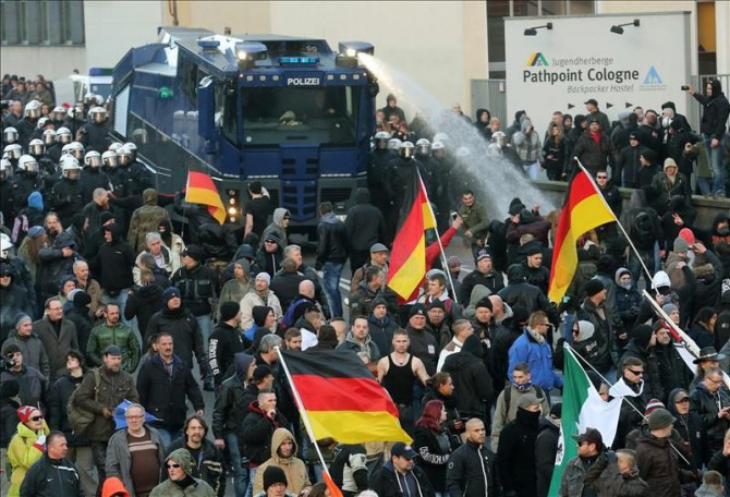 Un camión de la policia antidisturbios dispersa con chorros de agua una manifestación convocada en Colonia por el movimiento Pegida