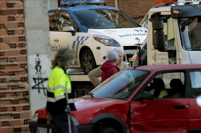 La grúa retira un coche policial que ha chocado contra otro vehículo al perseguir a dos hombres, uno de los cuales ha sido detenido, tras una agresión a un árbitro de un partido de fútbol de categoría benjamín, disputado en Salamanca, después de que los dos supuestos agresores huyeran por las calles del barrio de Los Pizarrales.