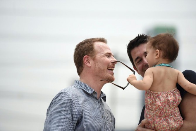 El estadounidense Gordon Lake (I) y el español Manuel Valero (D) juegan con Carmen, concebida por vientre de alquiler, tras una audiencia sobre su custodia en el Tribunal central de la familia en Bangkok, el 30 de marzo 