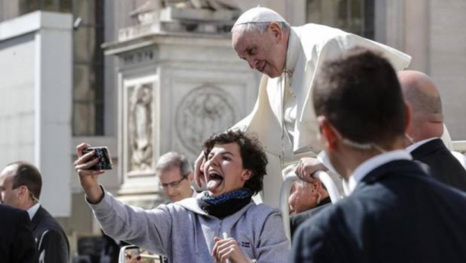 El Papa Francisco posa para un selfie con una joven a su llegada a la audiencia general de los miércoles en la plaza de San Pedro del Vaticano