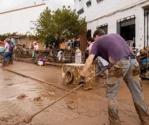 Varias personas colaboran en la limpieza de una calle tras el paso de la DANA